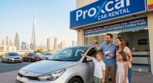 A happy family picking up a budget-friendly rental car outside a Proxcar Car Rental storefront in Dubai, with the Burj Khalifa and city skyline in the background.